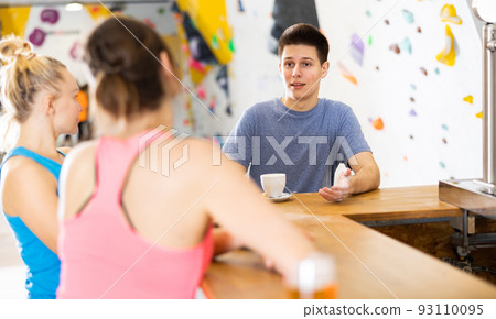 Young man talking with women in climbing center during break Young man talking with women in climbing center during break 93110095