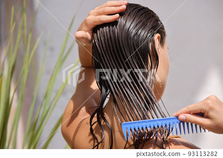 Young Female Model Putting Refreshing Mask On Long Wet Hair With Wooden Comb Young Female Model Putting Refreshing Mask On Long Wet Hair With Wooden Comb 93113282