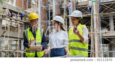 Structural engineer and architect discussing and working with blueprints at the outdoors construction site 93113970