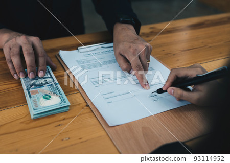 Partner give bribe money in envelope to another businessman and pointing at sign permit contract. Corruption and Anti Bribery concept. 93114952