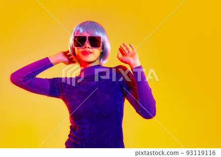 Cyber punk girl concept, asian woman in purple sweatshirt silver and blue short hair style wearing sunglasses posing like robot islated yellow background 93119116