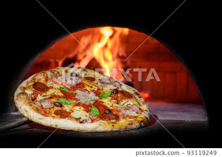 Delicious Italian pizza in a shovel putting in wood burning oven 93119249