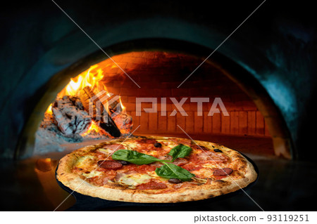 Delicious Italian pizza in a shovel putting in wood burning oven 93119251