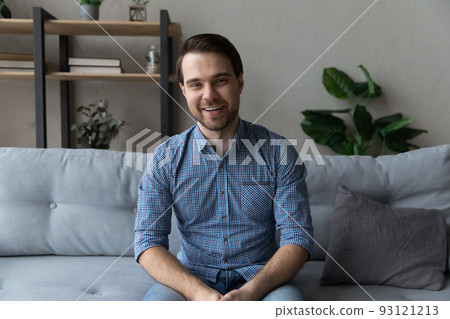 Smiling young man sit on sofa looking at camera 93121213