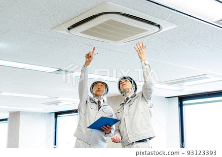 Two men checking the air conditioner Two men checking the air conditioner 93123393