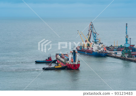 container ship is moored with the help of tugboats to a cargo berth, 93123483