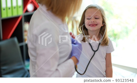 Happy smiling girl using medical stethoscope at doctor appointment Happy smiling girl using medical stethoscope at doctor appointment 93123548
