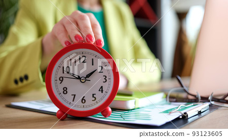 Woman putting red alarm clock on desk, time management and deadline Woman putting red alarm clock on desk, time management and deadline 93123605