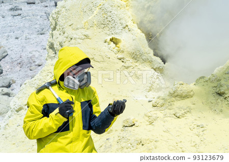 male volcano scientist with a geological hammer and in a respirator on the slope of a volcano nearby among toxic fumes 93123679