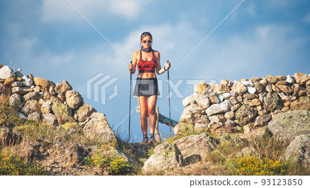 A sporty young woman with trekking sticks 93123850