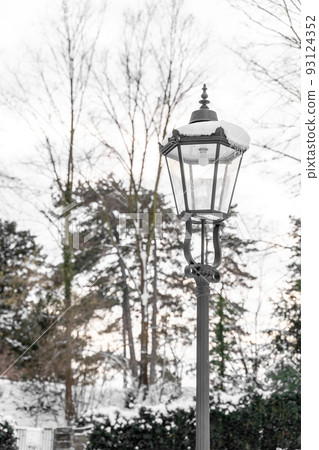 Retro classic snow-covered street light with modern electric balb in calm park Retro classic snow-covered street light with modern electric balb in calm park 93124352