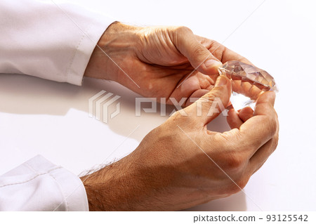 Closeup hands of jeweler holding huge gems at work in jewelry. Desktop for craft jewelry making with professional tools. Closeup hands of jeweler holding huge gems at work in jewelry. Desktop for craft jewelry making with professional tools. 93125542