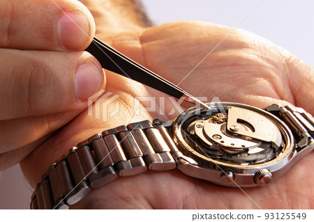 Watchmaker's job. Closeup male hands holding mechanical watches isolated over white background. Concept of vintage retro mechanisms, work, ad 93125549