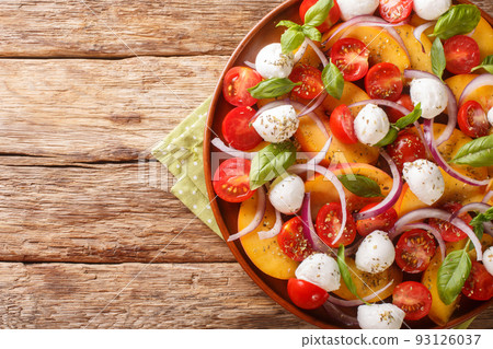 Peach tomato basil salad closeup on wooden background. Horizontal top view 93126037