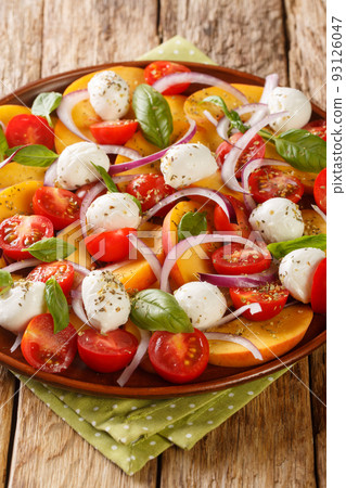 Caprese salad with peaches, mozzarella, cherry tomatoes, onions and basil close-up in a plate. Vertical Caprese salad with peaches, mozzarella, cherry tomatoes, onions and basil close-up in a plate. Vertical 93126047