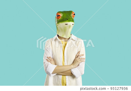 Woman in funny frog mask with sceptical face expression standing with her arms folded Woman in funny frog mask with sceptical face expression standing with her arms folded 93127936