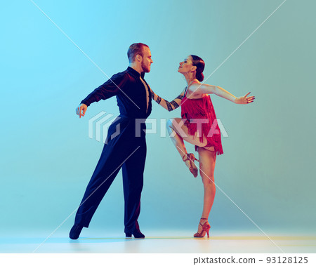 Dynamic portrait of professional dancers in stage attires dancing ballroom dance isolated on blue background. Concept of art, beauty, music, style. 93128125