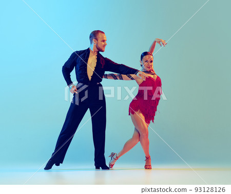 Studio shot of young couple, professional dancers dancing ballroom dance isolated on blue background. Concept of art, beauty, music, style. 93128126