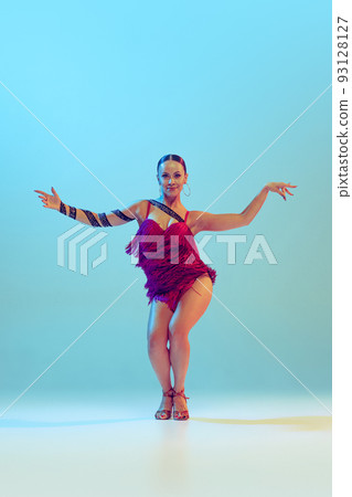 Portrait of young graceful flexible woman dancing ballroom dance without partner isolated on blue background in neon light. Concept of art, beauty Portrait of young graceful flexible woman dancing ballroom dance without partner isolated on blue background in neon light. Concept of art, beauty 93128127