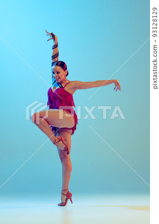Portrait of young graceful flexible woman dancing ballroom dance without partner isolated on blue background in neon light. Concept of art, beauty Portrait of young graceful flexible woman dancing ballroom dance without partner isolated on blue background in neon light. Concept of art, beauty 93128129