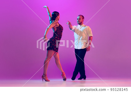 Beautiful coupleof dancers in adorable attires dancing ballroom dance isolated on purple background. Concept of art, beauty, music, style. Beautiful coupleof dancers in adorable attires dancing ballroom dance isolated on purple background. Concept of art, beauty, music, style. 93128145