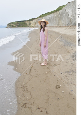 Taking a portrait of a woman in her 20s wearing a straw hat and overalls on the coast of Otobe, Hokkaido in summer 93128180