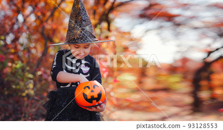 Young girl in black costume goes trick or treating 93128553