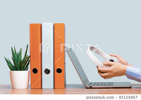 Laptop and hands with headphones on white desk Laptop and hands with headphones on white desk 93128867
