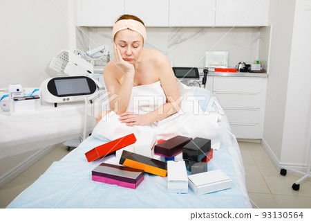Portrait of an elderly woman in a beauty salon. The woman is puzzled by the right choice of cosmetics. Portrait of an elderly woman in a beauty salon. The woman is puzzled by the right choice of cosmetics. 93130564