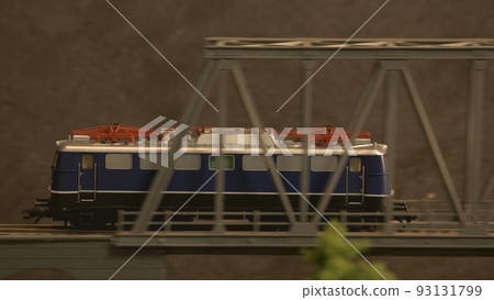 Miniature diesel train moving through the bridge. Model of vintage diesel train in motion. Miniature diesel train moving through the bridge. Model of vintage diesel train in motion. 93131799