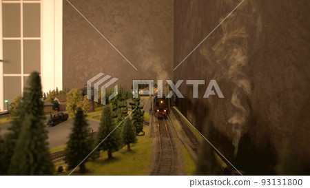 Front view of electric toy locomotive moving on railroad. Miniature railway station with moving train. Perfect gift for kids. Front view of electric toy locomotive moving on railroad. Miniature railway station with moving train. Perfect gift for kids. 93131800
