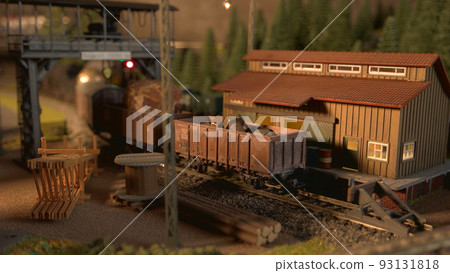 Model freight train arriving at railway station. Miniature railway station with moving cargo train. 93131818