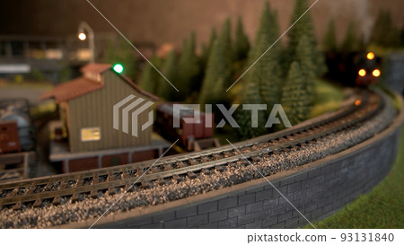 Miniature freight train moving on miniature railroad. Model of railway road with moving cargo train. Miniature freight train moving on miniature railroad. Model of railway road with moving cargo train. 93131840