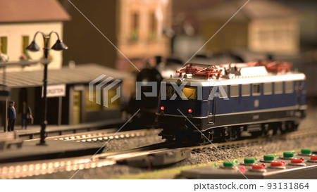 Mini train station modelling. Model of railway station with moving train. Model electric locomotive moving on model railroad. Mini train station modelling. Model of railway station with moving train. Model electric locomotive moving on model railroad. 93131864