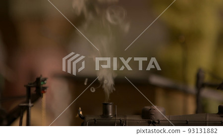 Close up smoking chimney of toy steam locomotive. Abstract blurred background. Retro toy locomotive with a smoke. 93131882