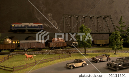 Model of steam locomotive train crossing the bridge. Model of freight locomotive moving under the bridge. Scenic summer park backgrouund. 93131891