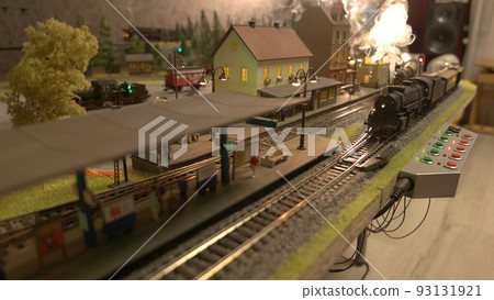 Miniature train railway station. A model of a train moves down the miniature railroad. Miniature of city. Miniature train railway station. A model of a train moves down the miniature railroad. Miniature of city. 93131921