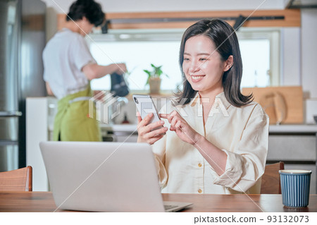 A woman who operates a smartphone in telework and a man who does housework A woman who operates a smartphone in telework and a man who does housework 93132073