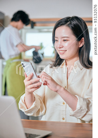 A woman who operates a smartphone in telework and a man who does housework A woman who operates a smartphone in telework and a man who does housework 93132076