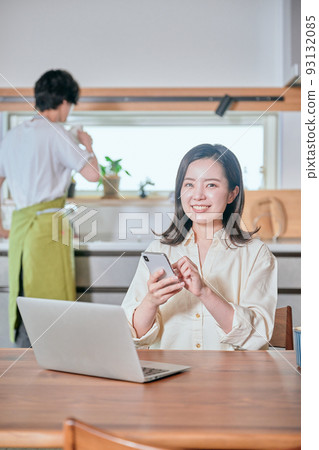 A woman who operates a smartphone in telework and a man who does housework A woman who operates a smartphone in telework and a man who does housework 93132085