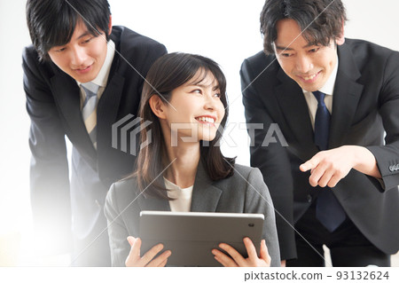 A young business woman with a tablet and a man watching over it A young business woman with a tablet and a man watching over it 93132624