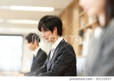 A young business person in a suit working on a PC A young business person in a suit working on a PC 93132637