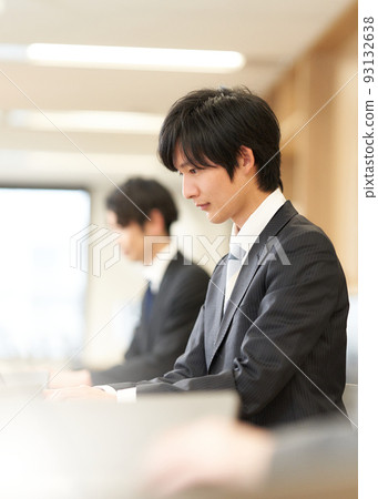 A young business person in a suit working on a PC A young business person in a suit working on a PC 93132638