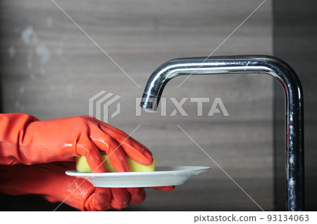 sponge , hand in red rubber gloves cleaning a plate with sponge  93134063