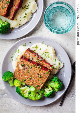 Lentil meatloaf pieces with mashed potatoes and broccoli on gray plate. Vegan christmas recipe. Lentil meatloaf pieces with mashed potatoes and broccoli on gray plate. Vegan christmas recipe. 93134399