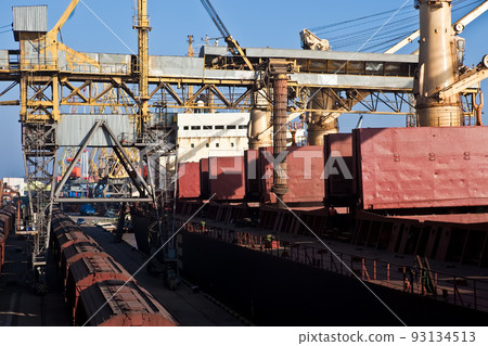 Loading grain into holds of sea cargo vessel in seaport from grain storage. Loading grain into holds of sea cargo vessel in seaport from grain storage. 93134513