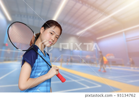 Badminton Athlete Asian player teen girl cute smiling portrait with indoor sport badminton court background Badminton Athlete Asian player teen girl cute smiling portrait with indoor sport badminton court background 93134762