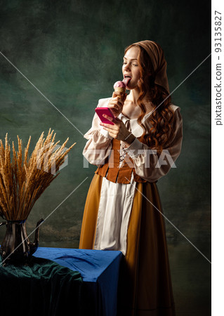 Young beautiful redhair girl with long curly hair like girl of renaissance eras isolated on dark background. Eras comparison, beauty, art, immitation 93135827