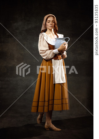 Vintage portrait of young adorable redhead girl in image of medieval person in renaissance style dress isolated on dark background. Comparison of eras 93135835