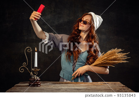 Vintage style. Young charming redhair girl with long curly hair like girl of renaissance eras isolated on dark background. Eras comparison, beauty, art, painting Vintage style. Young charming redhair girl with long curly hair like girl of renaissance eras isolated on dark background. Eras comparison, beauty, art, painting 93135843